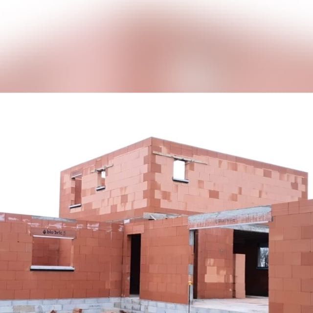 Charpente en bois d'une maison avec montants verticaux et entretoises diagonales sur un chantier ensoleillé.