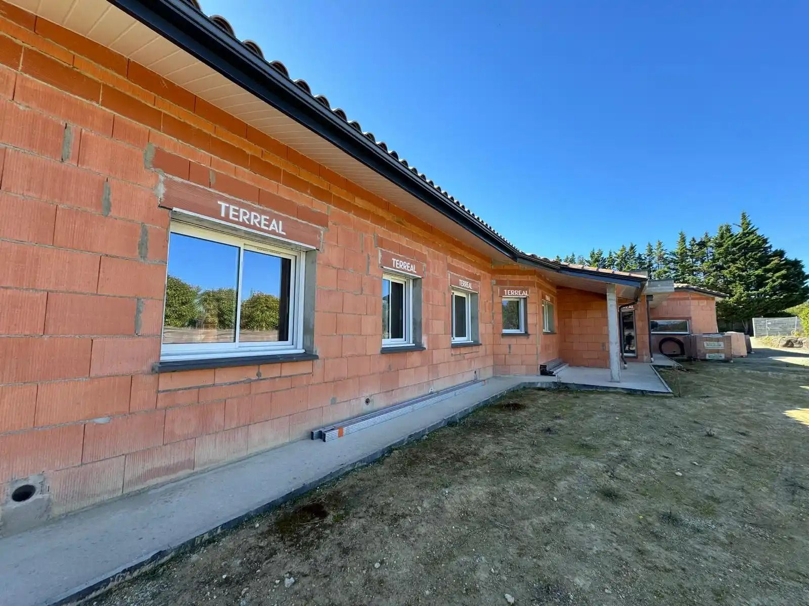 Extérieur d'un bâtiment en briques avec fenêtres et entrée couverte sous un ciel bleu clair