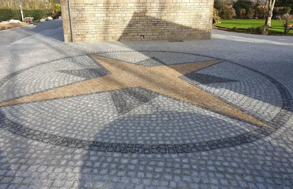 Place circulaire pavée avec un monument en pierre et des planches de bois croisées au soleil