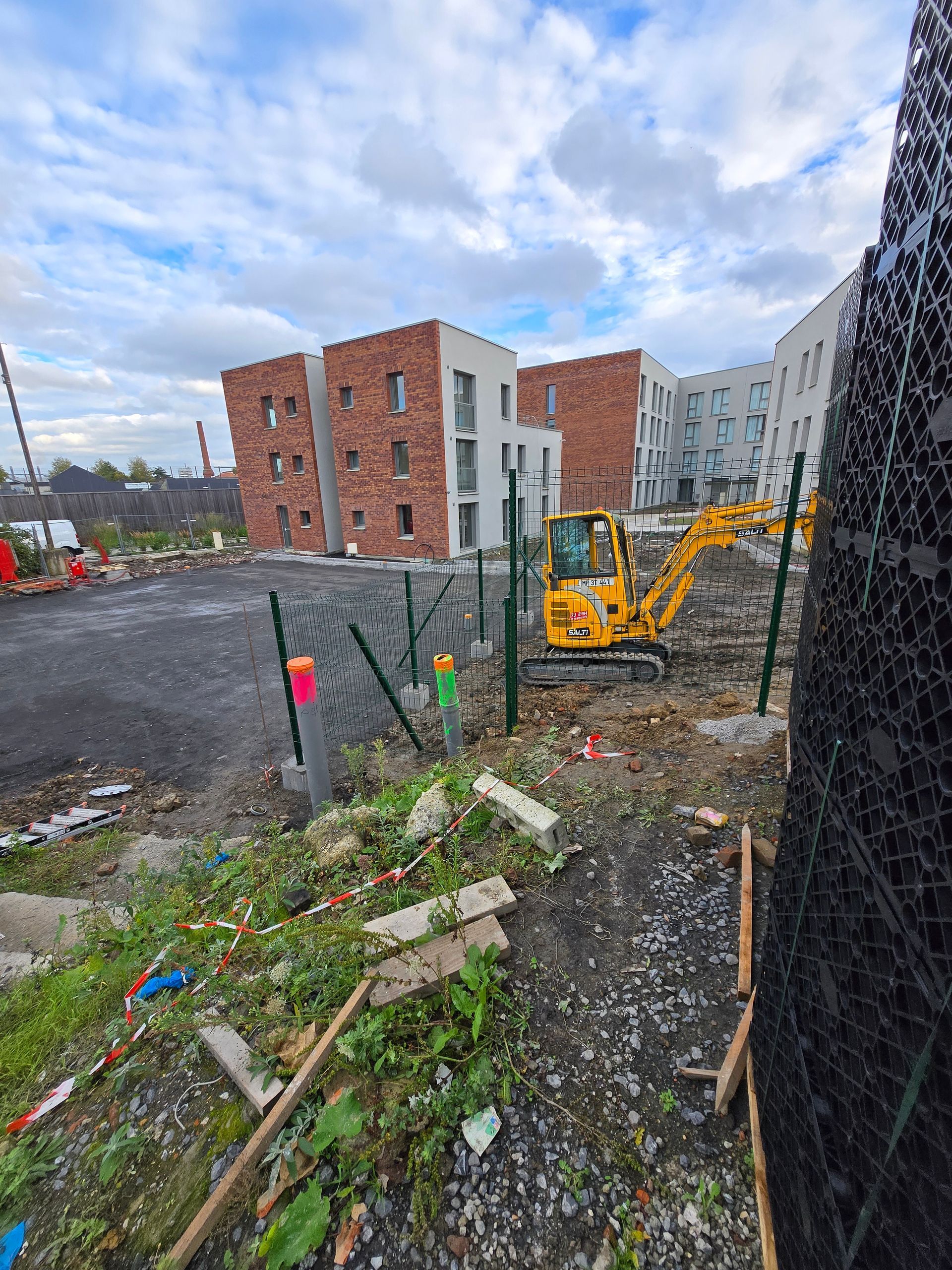 Tractopelle pour une pose de clôture dans une cour d'immeuble