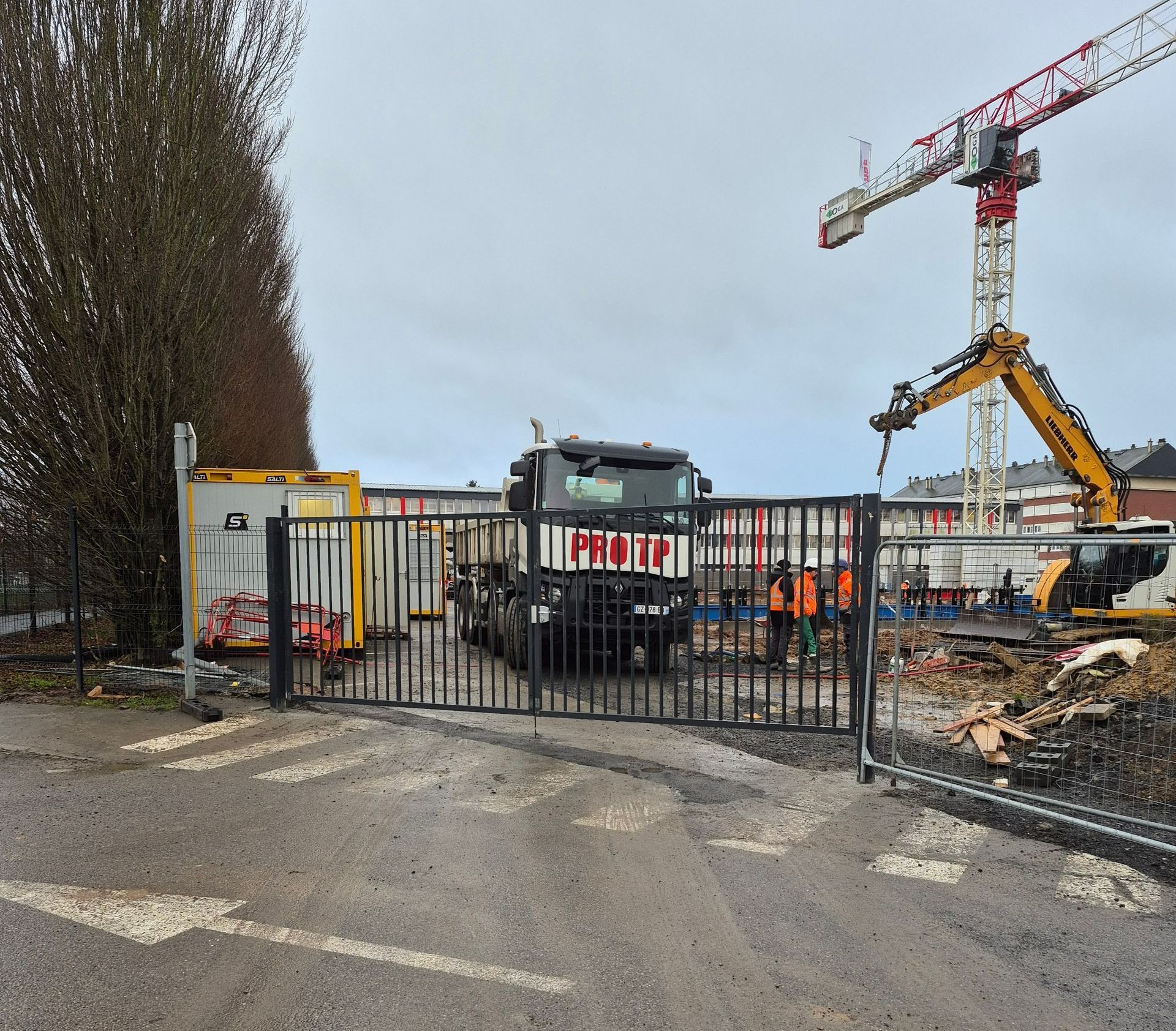Portail en acier peint, grue et camion sur un chantier de BTP