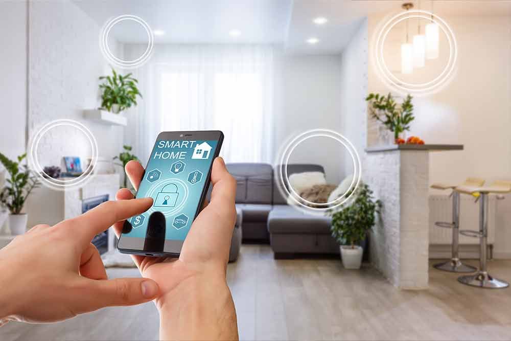 Eine Person nutzt ein Smartphone mit einer Smart-Home-App im Wohnzimmer, um Lichter und Geräte zu steuern.