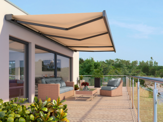 Ein Balkon mit einer Couch und einem Tisch unter einer Markise