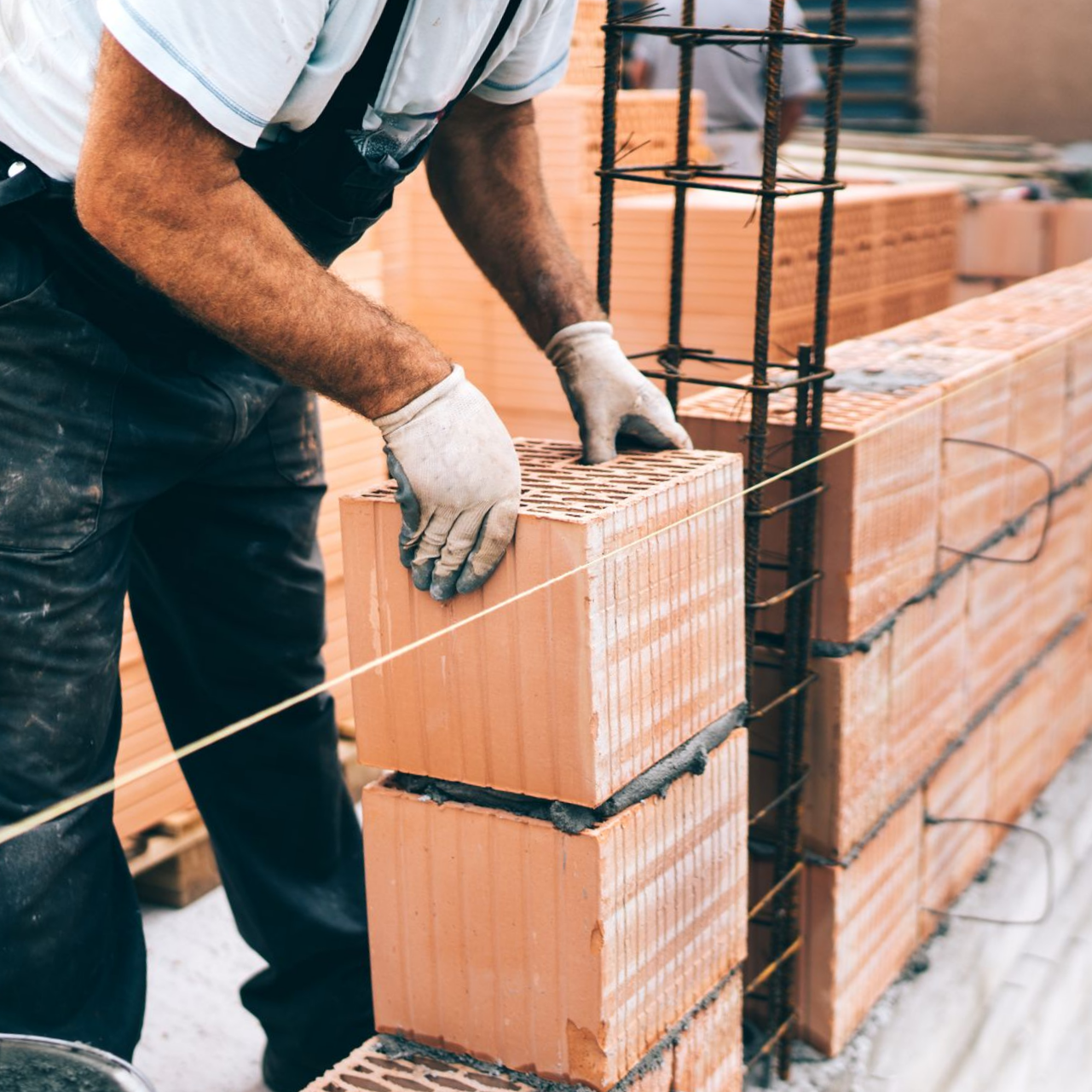 Un ouvrier du bâtiment pose des briques pour construire un mur.