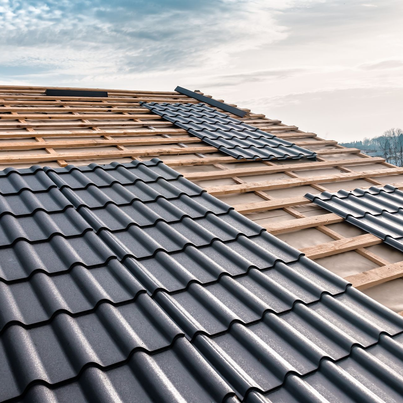 Pose de tuiles sur une charpente en bois.