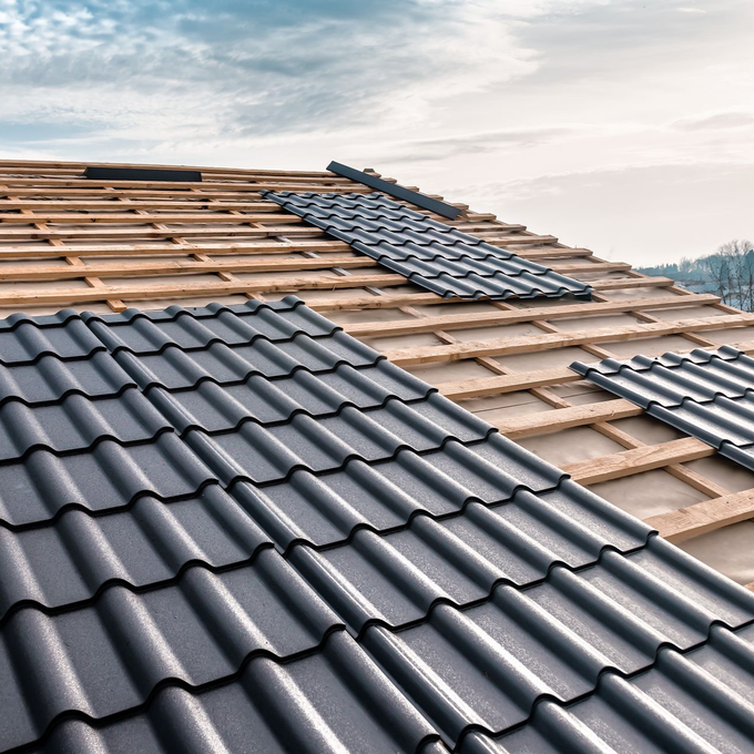 Pose de tuiles sur une charpente en bois.