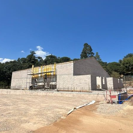 Chantier de construction avec un bâtiment en briques claires partiellement construit.