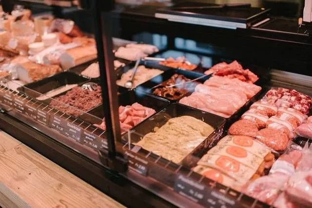 Fleischtheke mit verschiedenen Fleischsorten, darunter Hackfleisch und Würstchen.