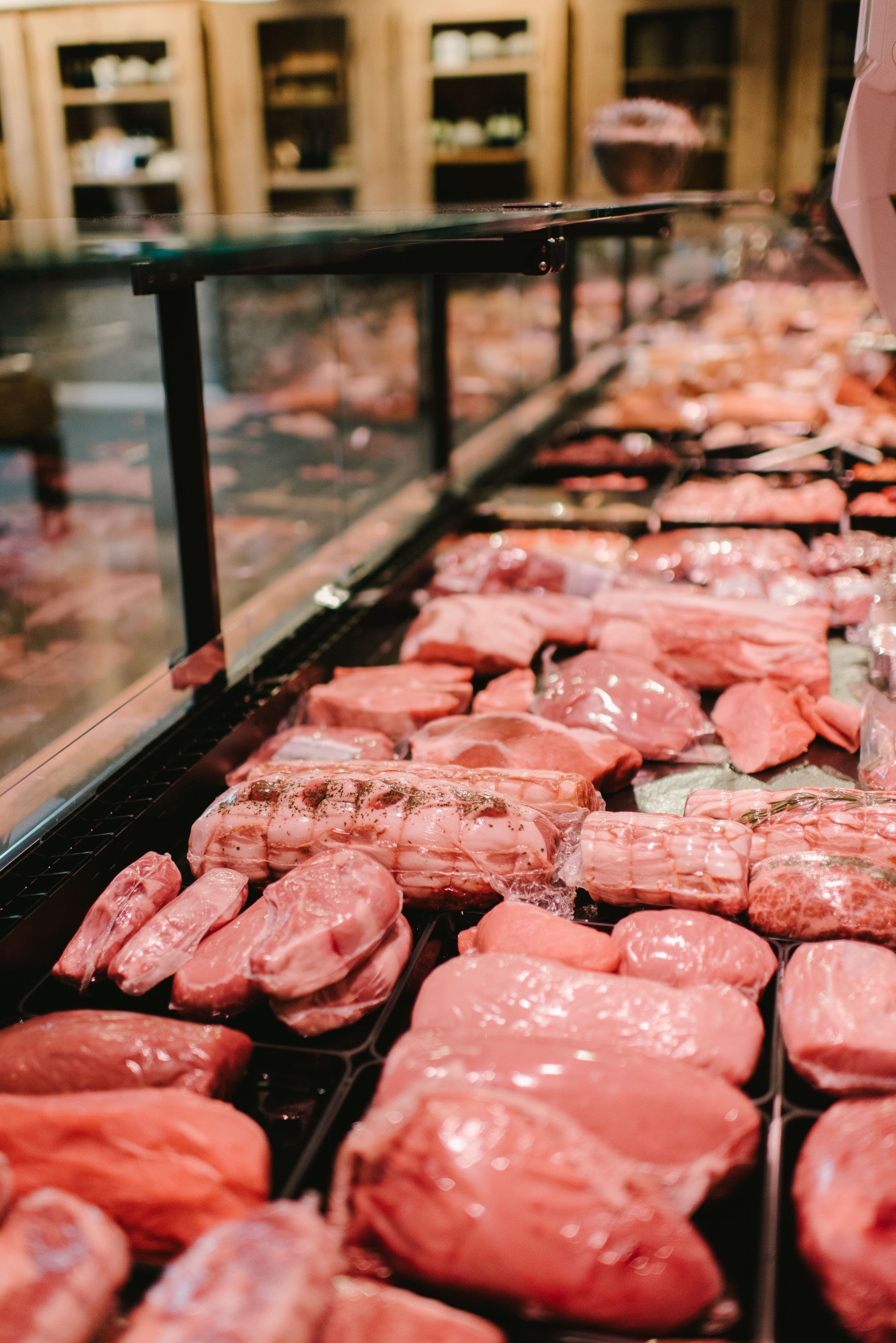 Mit Speck umwickelte Lebensmittel auf einem dunklen Backblech im Ofen, teilweise sichtbar.