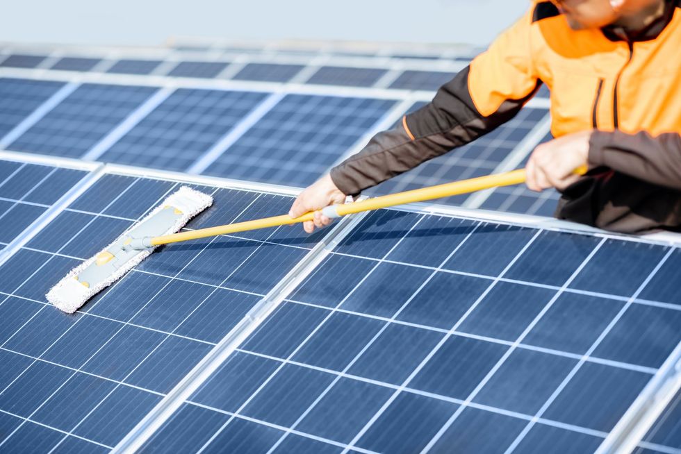 Ein Mann reinigt Solarmodule mit einem Mopp.