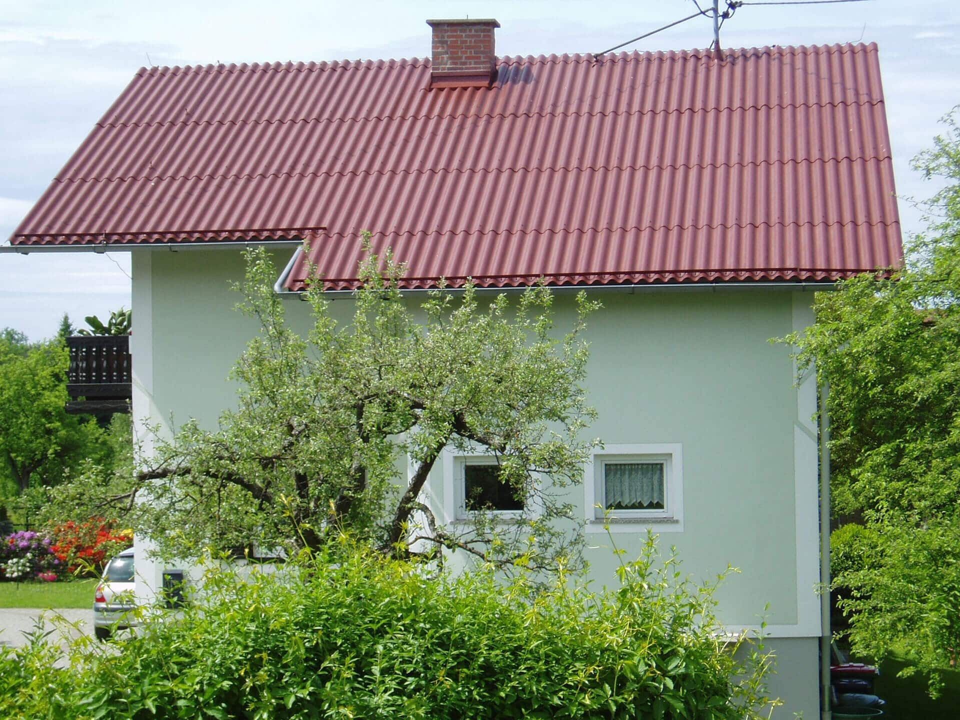 Ein weißes Haus mit einem roten Dach und einem Schornstein