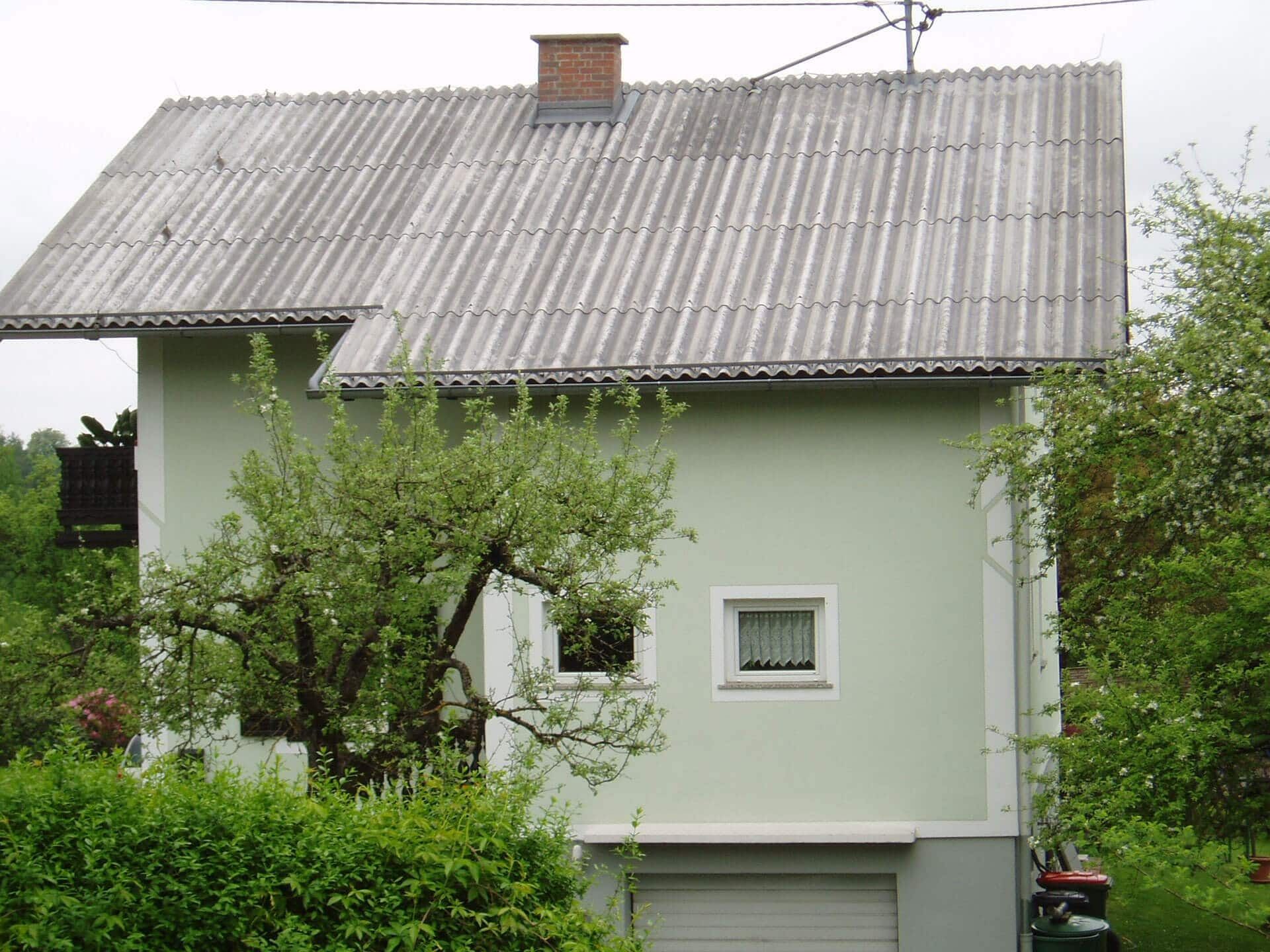 Ein grünes Haus mit einem grauen Dach und einem Schornstein