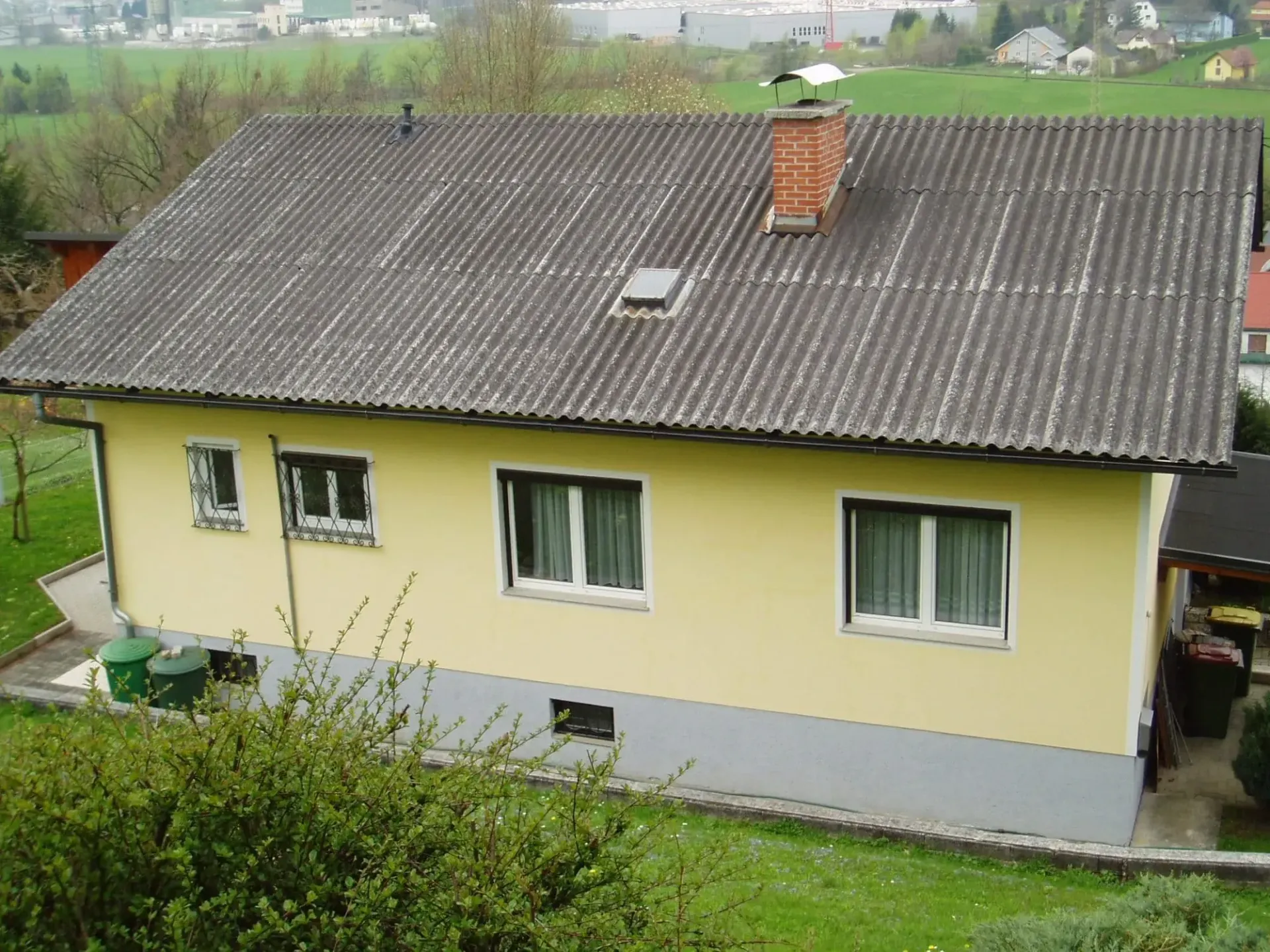 Ein gelbes Haus mit einem Dach, das mit Schindeln bedeckt ist