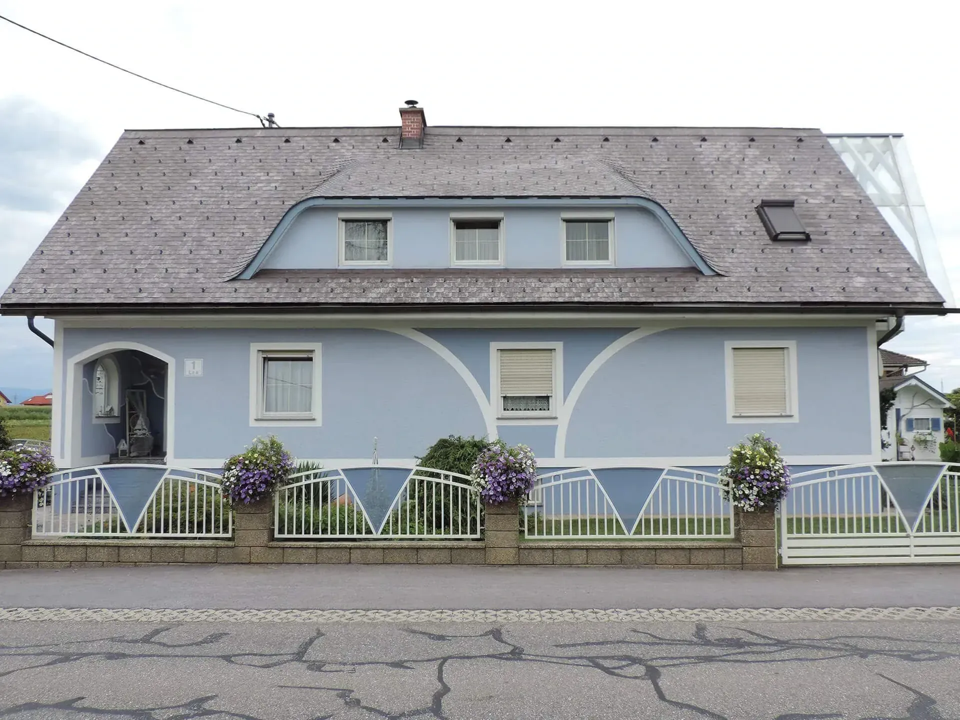Ein blaues Haus mit einem grauen Dach und einem Zaun