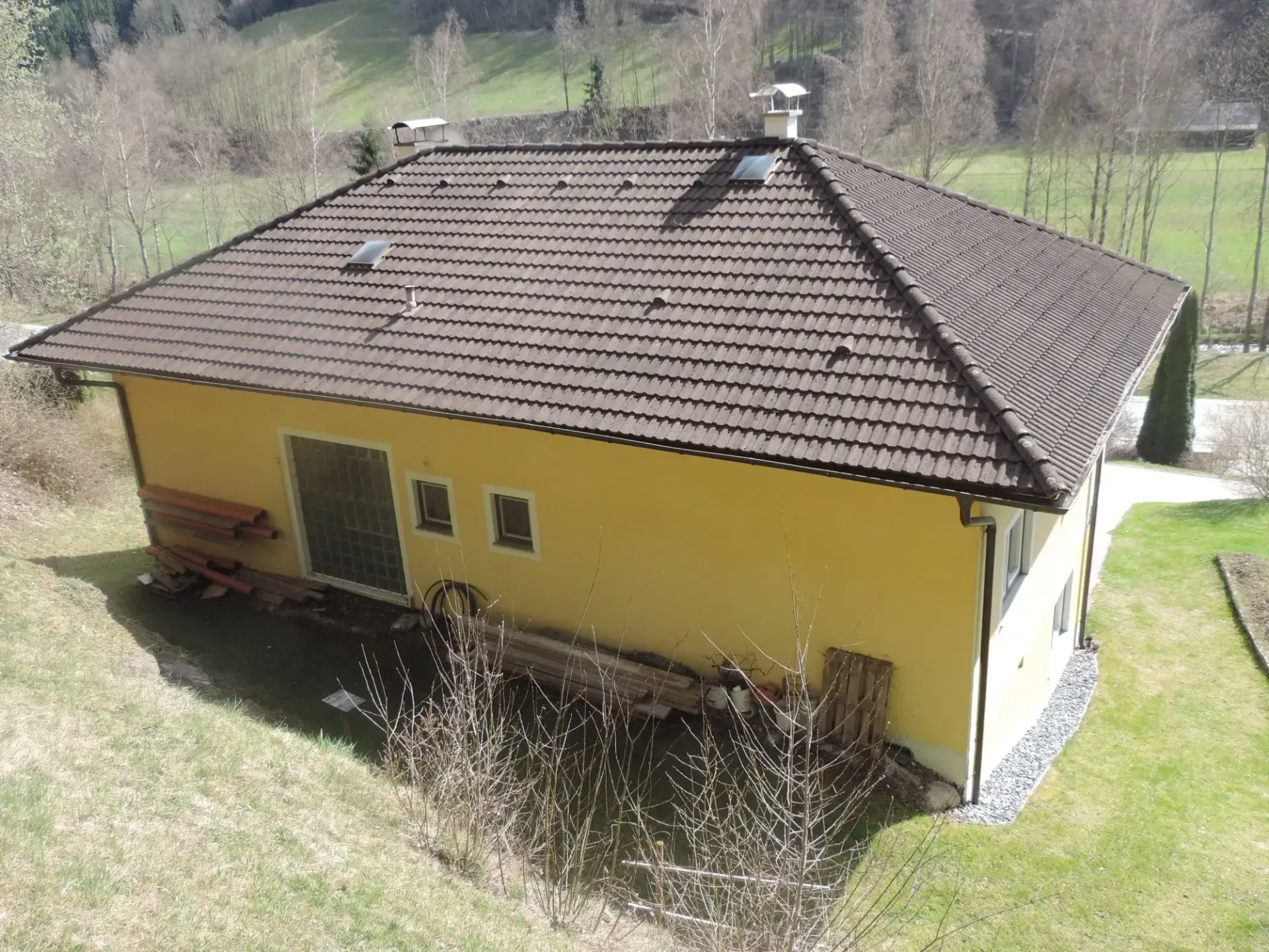 Ein kleines gelbes Haus mit einem braunen Ziegeldach