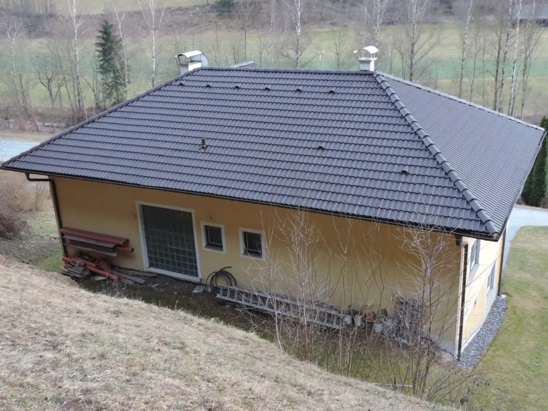 Auf einem grasbewachsenen Hügel steht ein kleines Haus mit Ziegeldach.