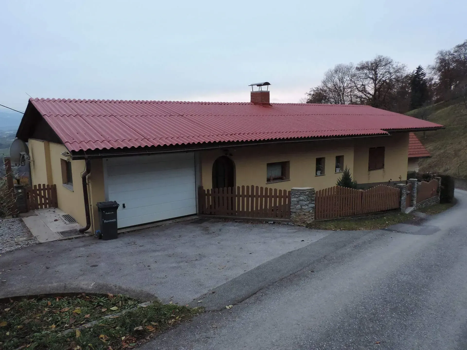 Ein Haus mit rotem Dach und weißem Garagentor
