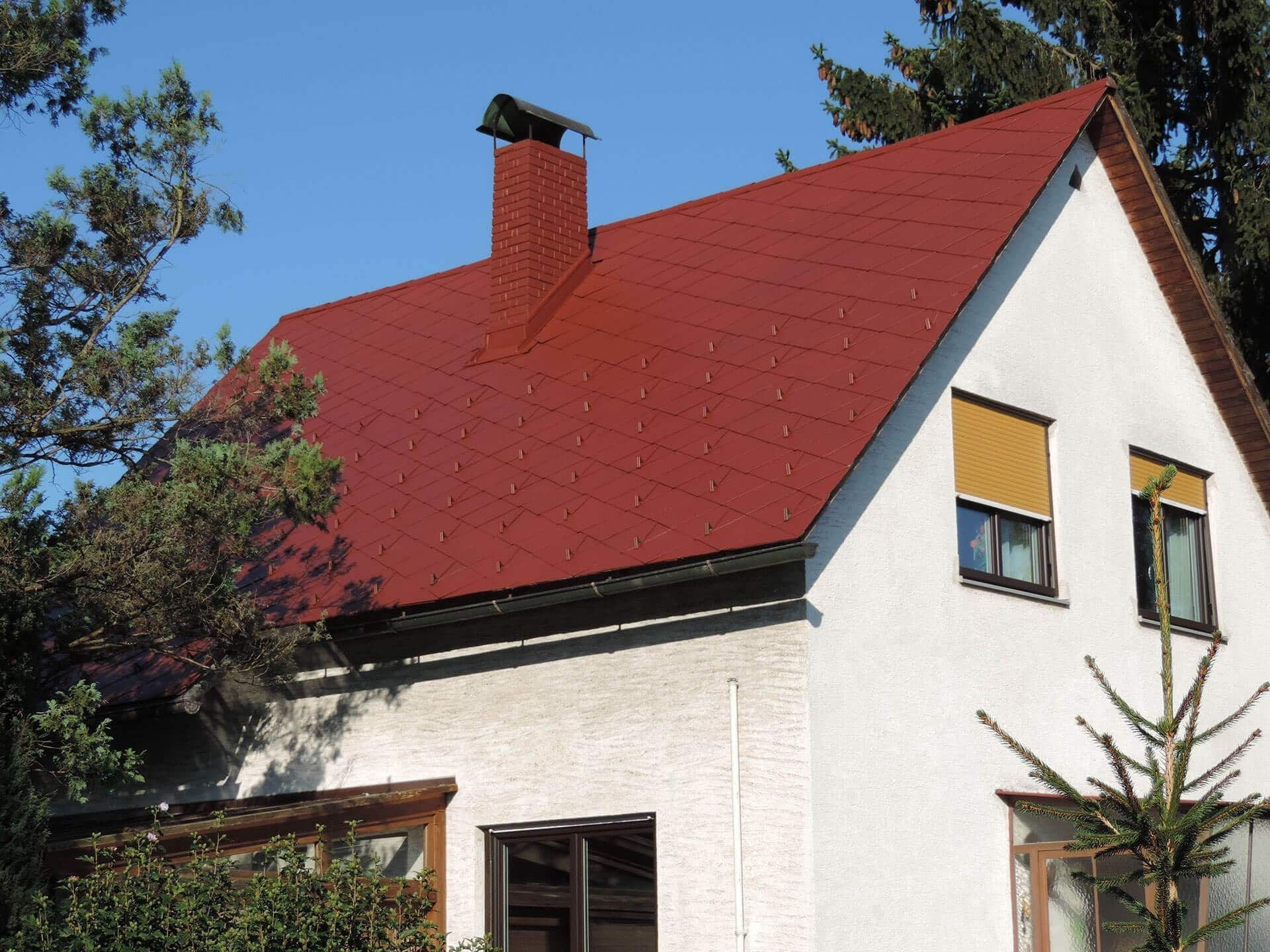 Ein weißes Haus mit einem roten Dach und einem Schornstein