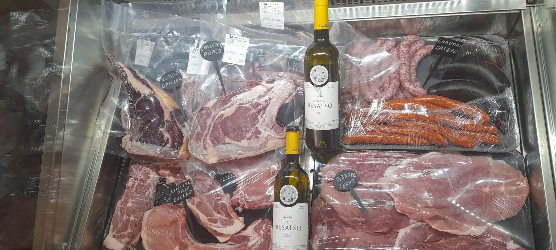 Una vitrina llena de carne y botellas de vino.