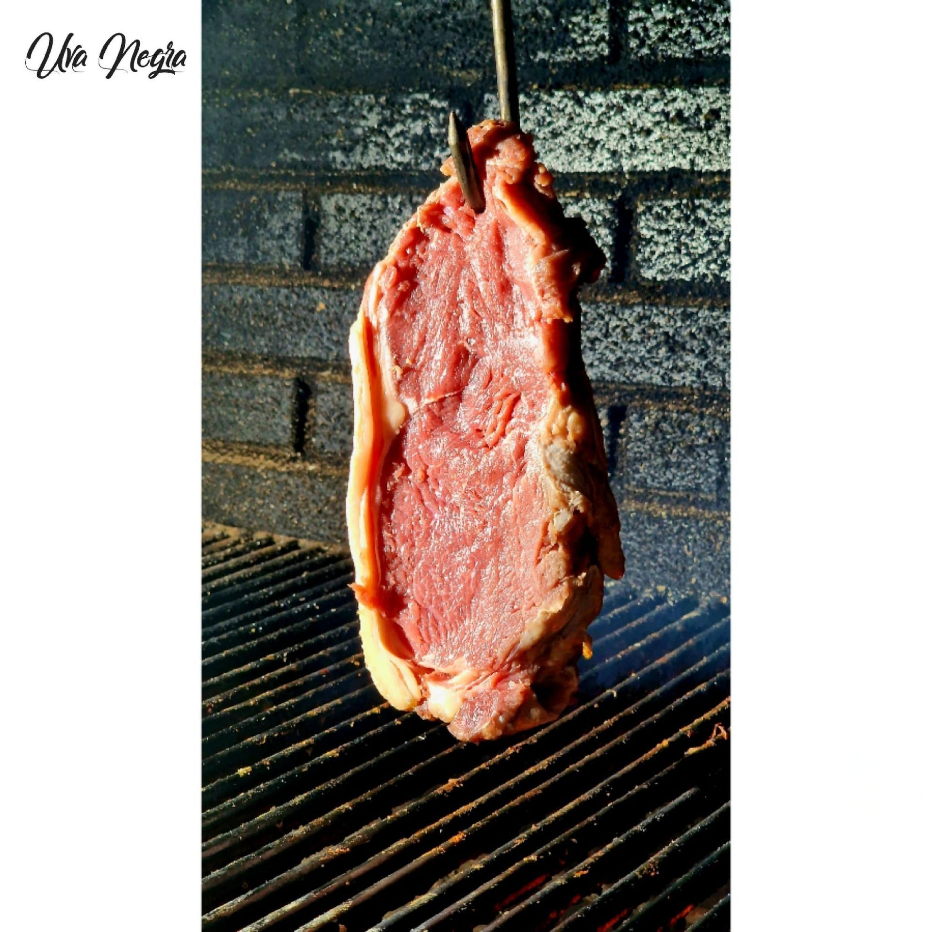 Un gran trozo de carne cuelga de un gancho en una parrilla.