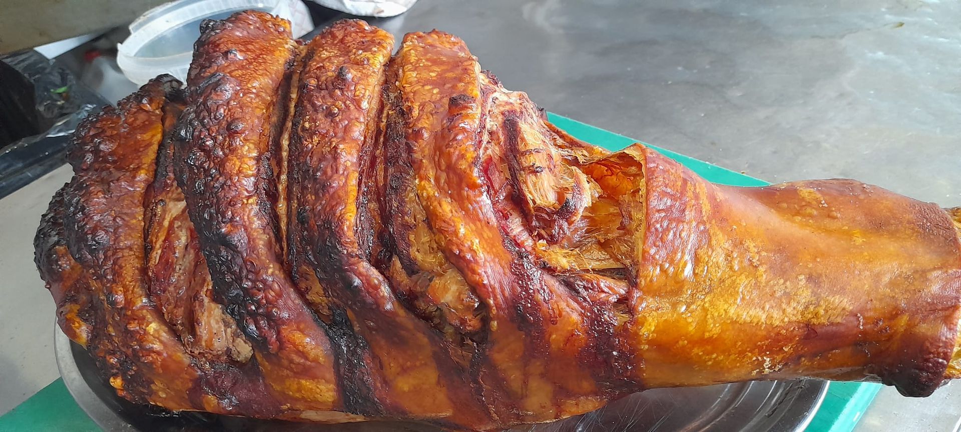 Un gran trozo de carne reposa en una bandeja verde sobre una mesa.