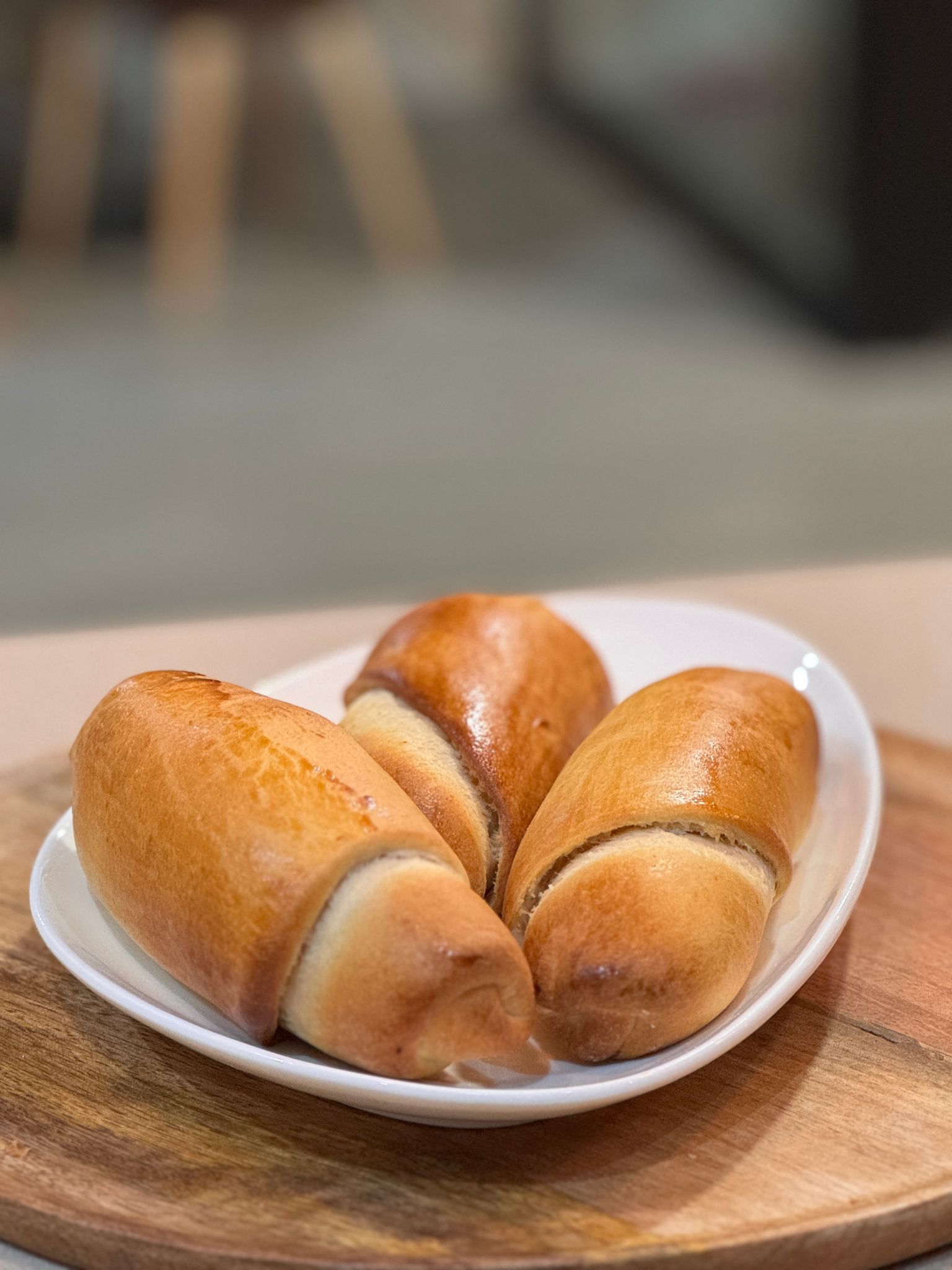 Hay tres rollos en un plato blanco sobre una tabla de cortar de madera.