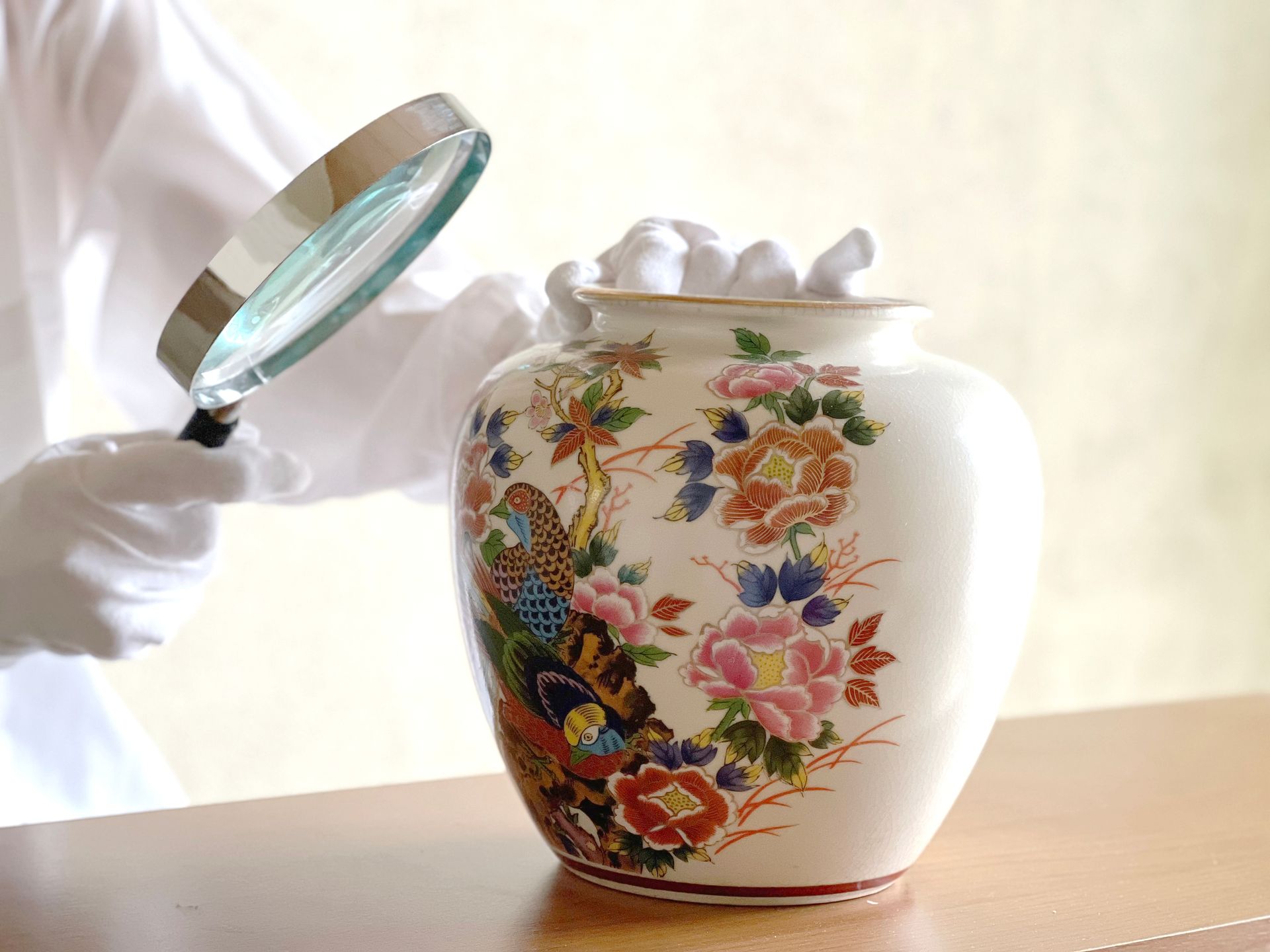 Un professionnel examinant un vase de Chine avec une loupe