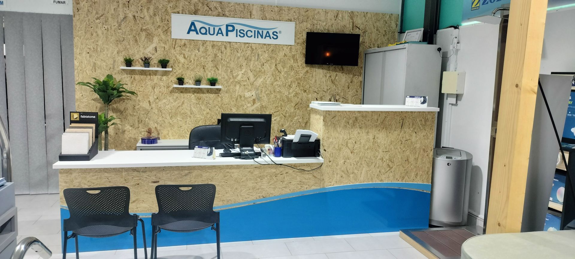 Uma área de recepção com uma mesa, cadeiras e um computador.