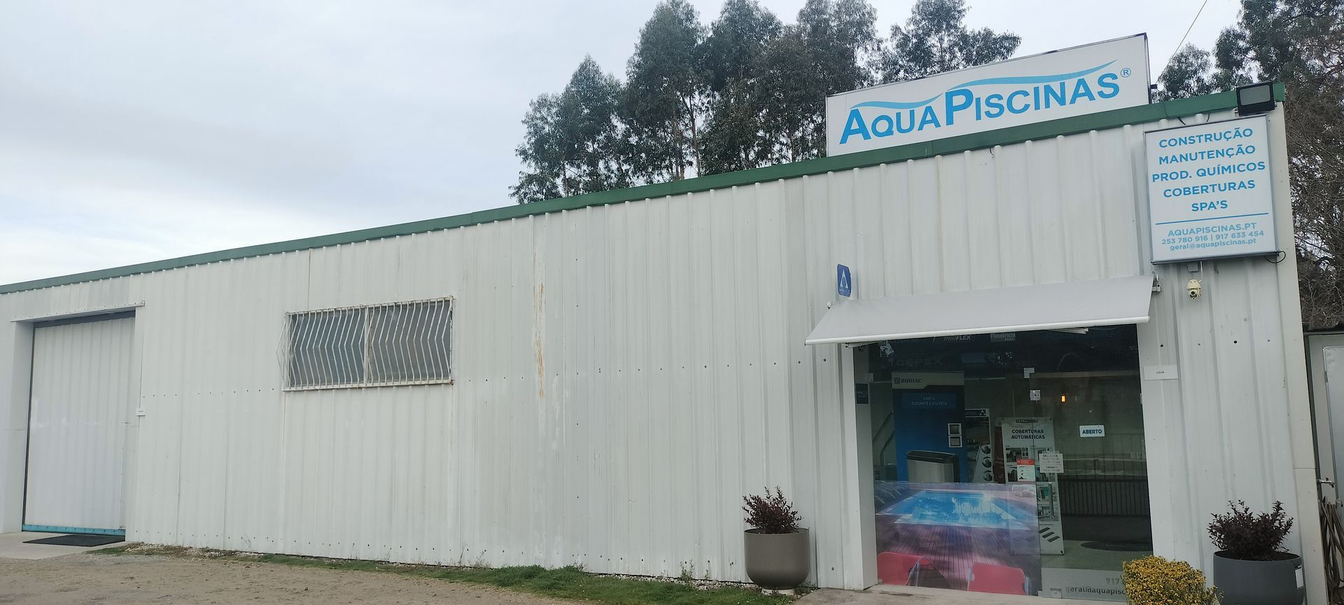 Um prédio branco com uma placa que diz aqua piscinas
