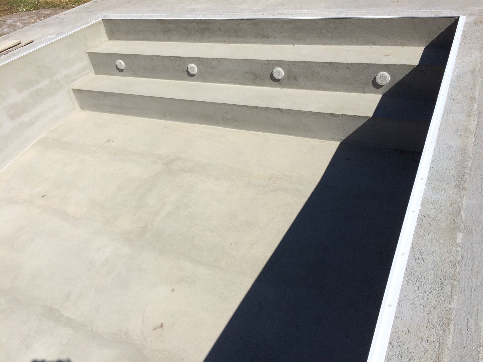 Uma piscina de concreto com degraus e uma borda preta