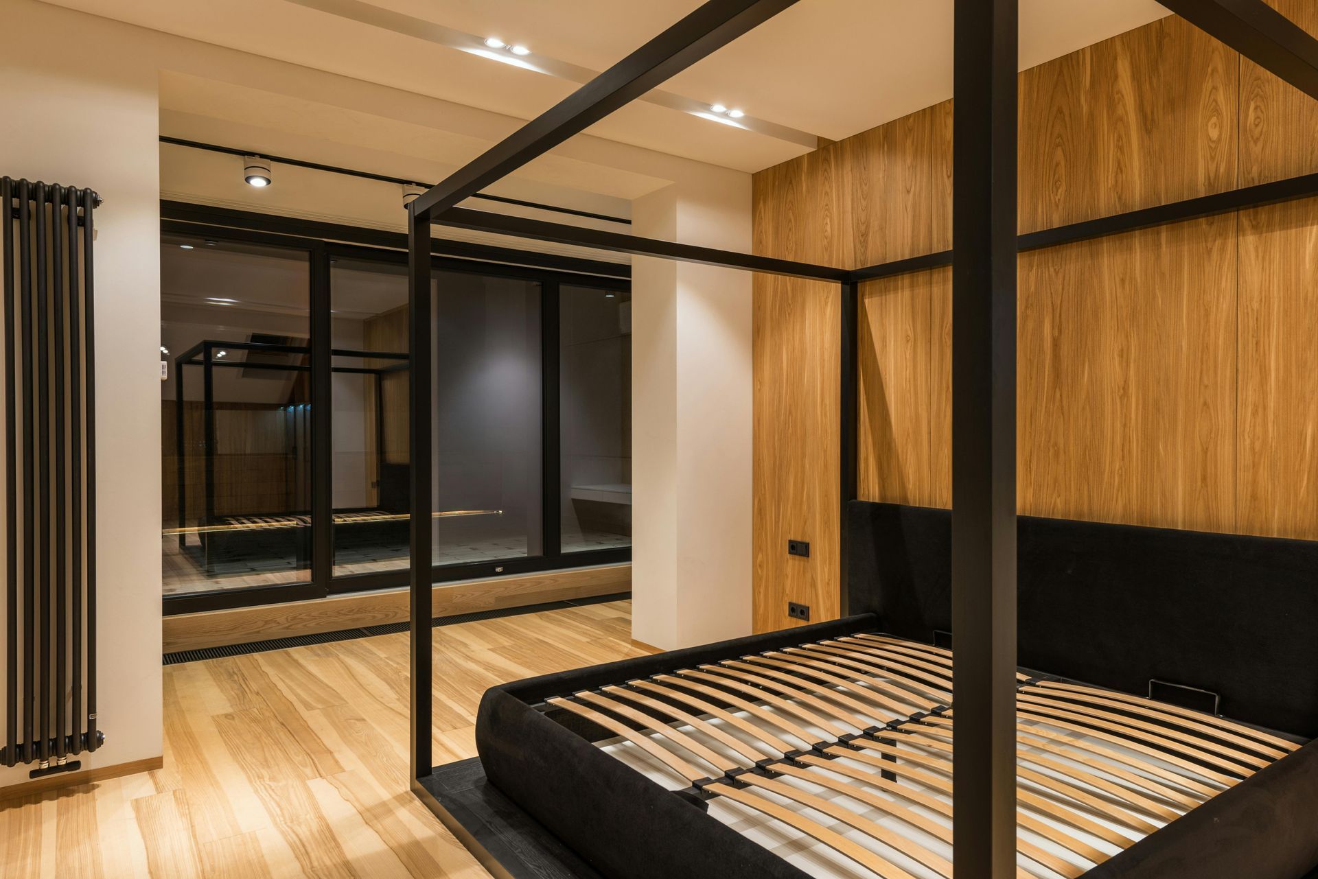 Este dormitorio moderno cuenta con una cama con dosel negra y somier de listones de madera