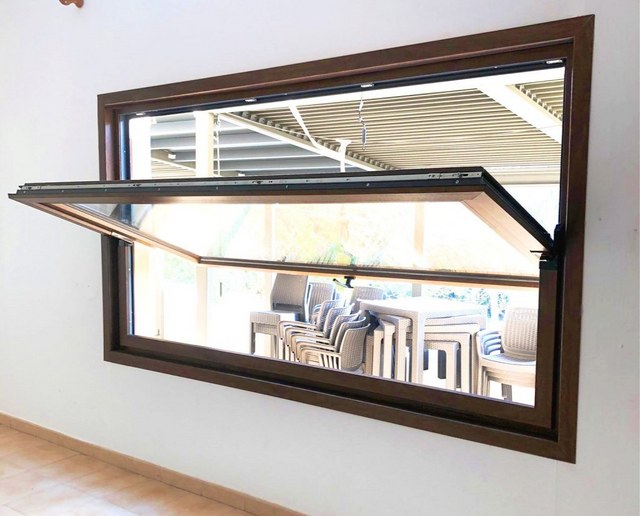 Ventana horizontal abierta en una pared, que deja ver un comedor con sillas a rayas en el interior.