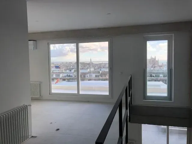 Interior de apartamento vacío con grandes ventanales con vistas a un horizonte nevado de la ciudad.
