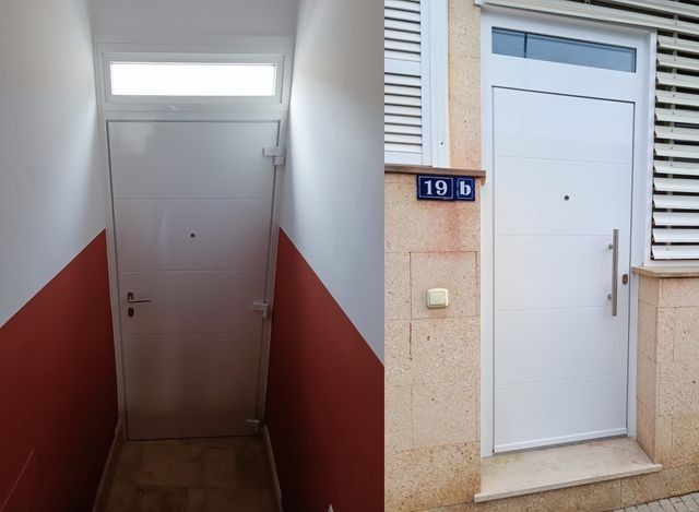 Dos puertas blancas de apartamentos en entradas estrechas, una en el interior con paredes rojas y otra en el exterior con una placa azul con un número.