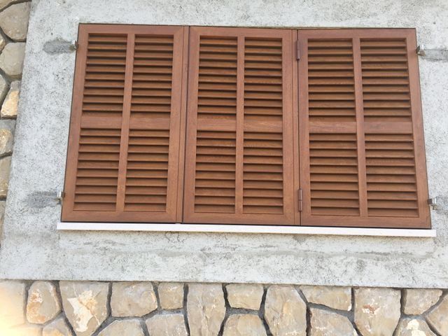 Persianas de madera marrón en la pared de piedra de un edificio.