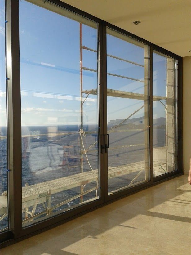 Habitación luminosa con ventanales del suelo al techo con vistas a un puente y al paisaje urbano.