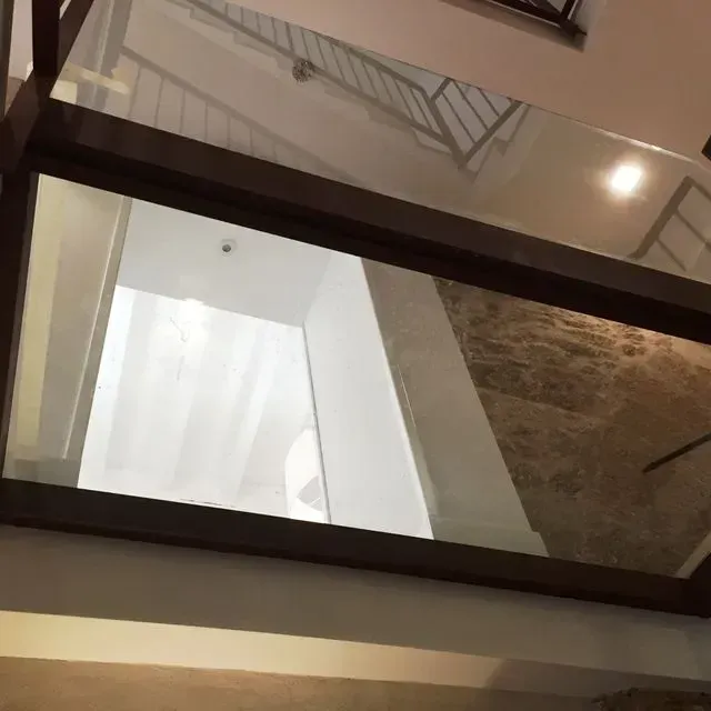 Vista de una escalera a través de una barandilla de cristal en un atrio interior moderno.