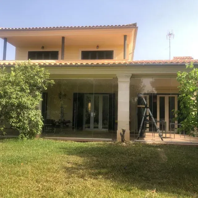 Patio trasero con una casa de dos pisos, césped verde y una escalera cerca de las puertas corredizas de vidrio.