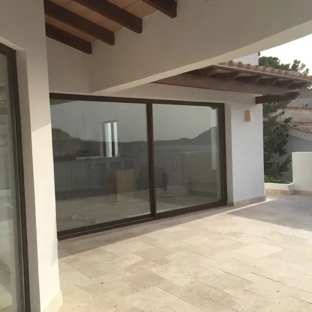 Patio moderno con grandes puertas corredizas de vidrio bajo un techo sombreado, con vistas a lo lejos.