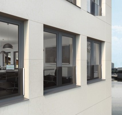 Exterior de edificio moderno con ventanas de marcos oscuros que reflejan una vista al paseo marítimo.