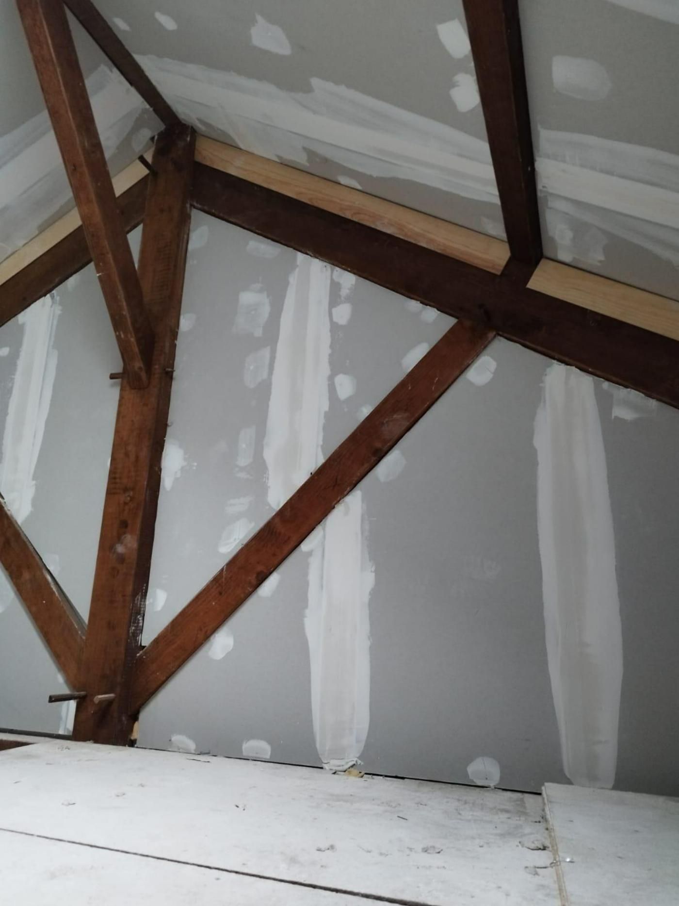 Intérieur du grenier montrant des poutres en bois et des cloisons sèches.