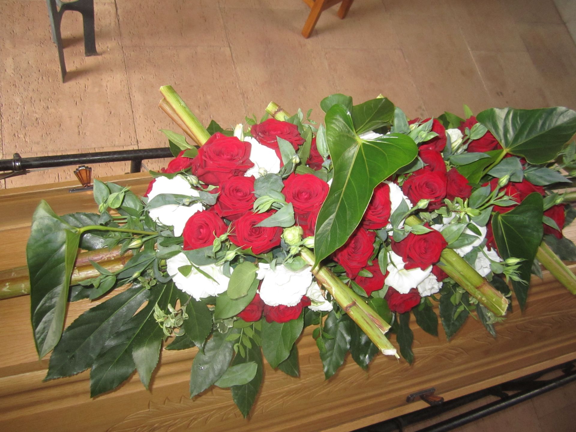 Blumenarrangement aus roten und weißen Blumen auf einer Holzoberfläche.