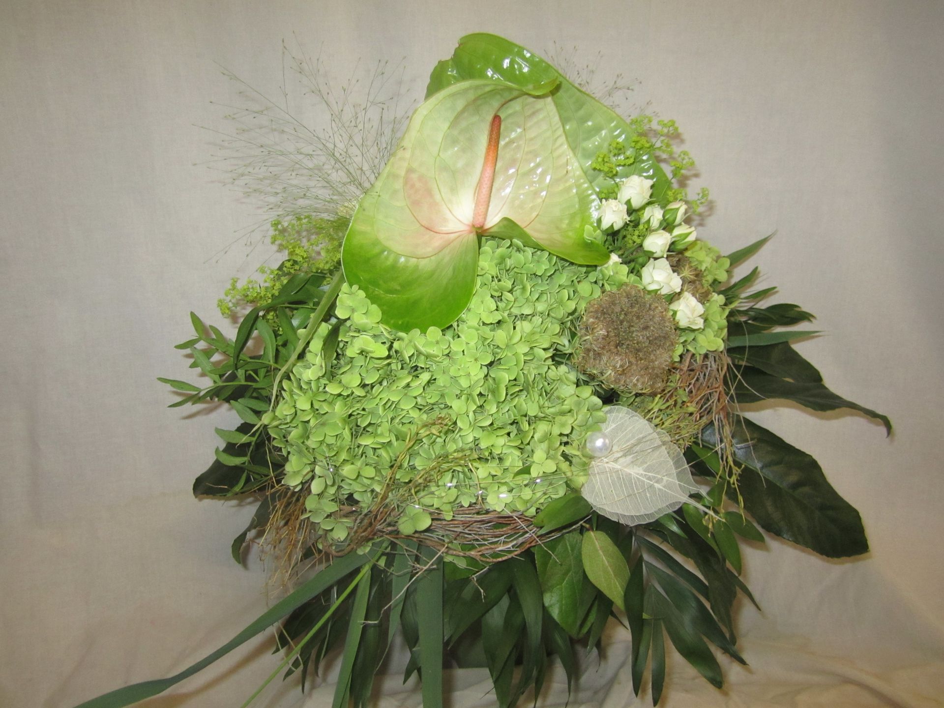 Grün-weißes Blumenarrangement mit Anthurie, Hortensie und Grünpflanzen.