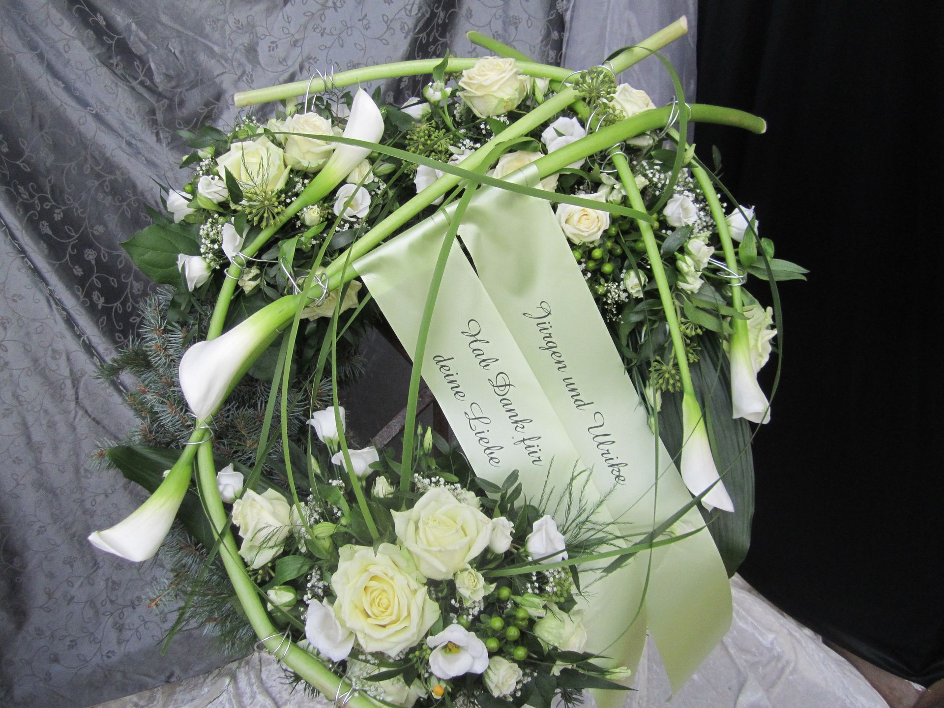 Weißer Blumenkranz mit grünem Band.