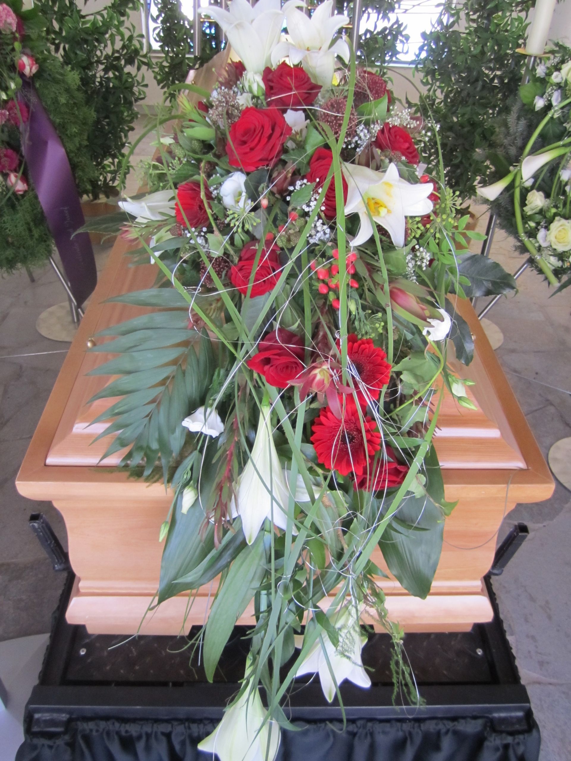 Schatulle mit Blumenarrangement aus roten Rosen und weißen Lilien.
