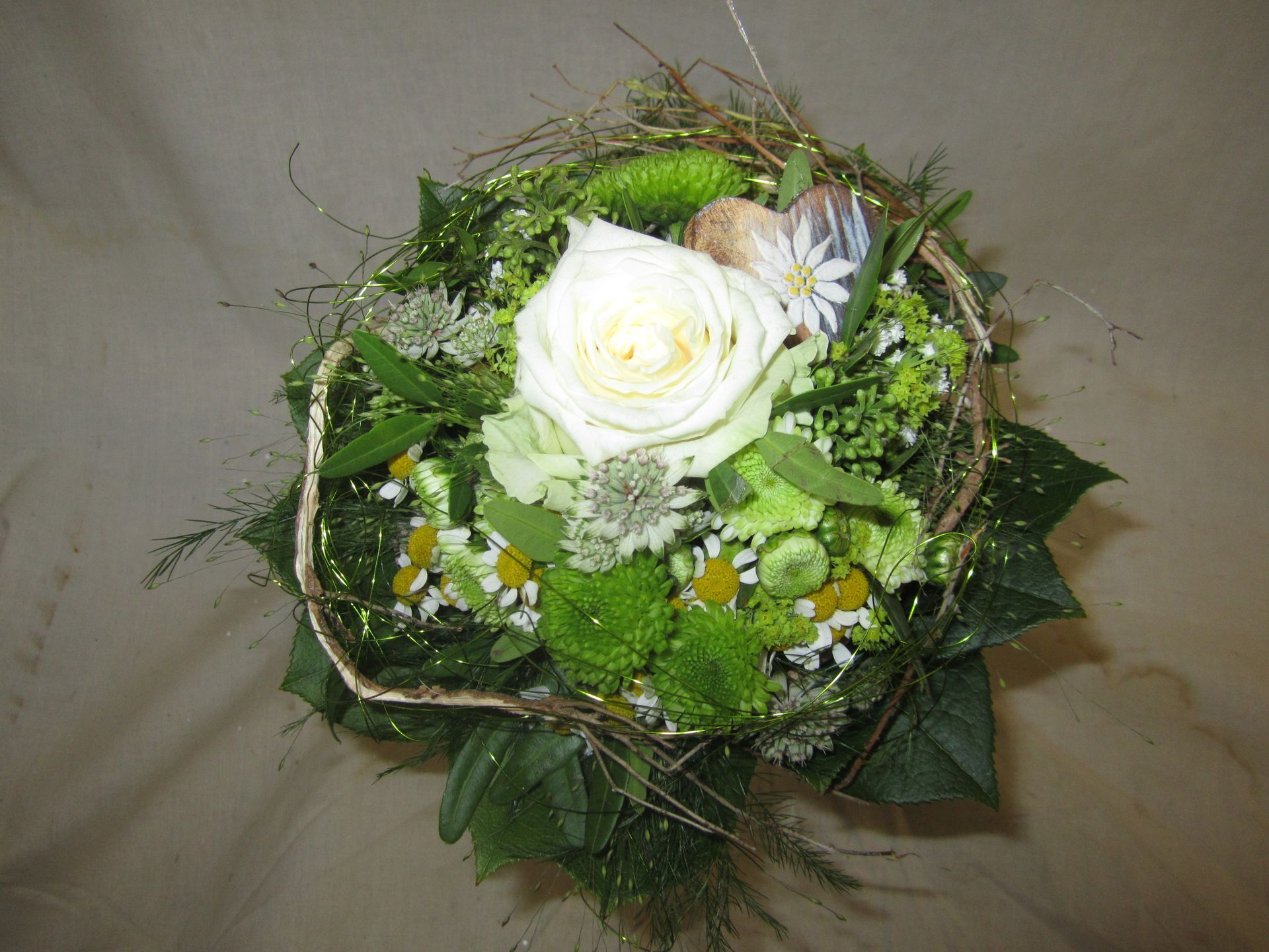 Weißer Rosenstrauß mit grünem Laub und ein paar kleinen Gänseblümchen.