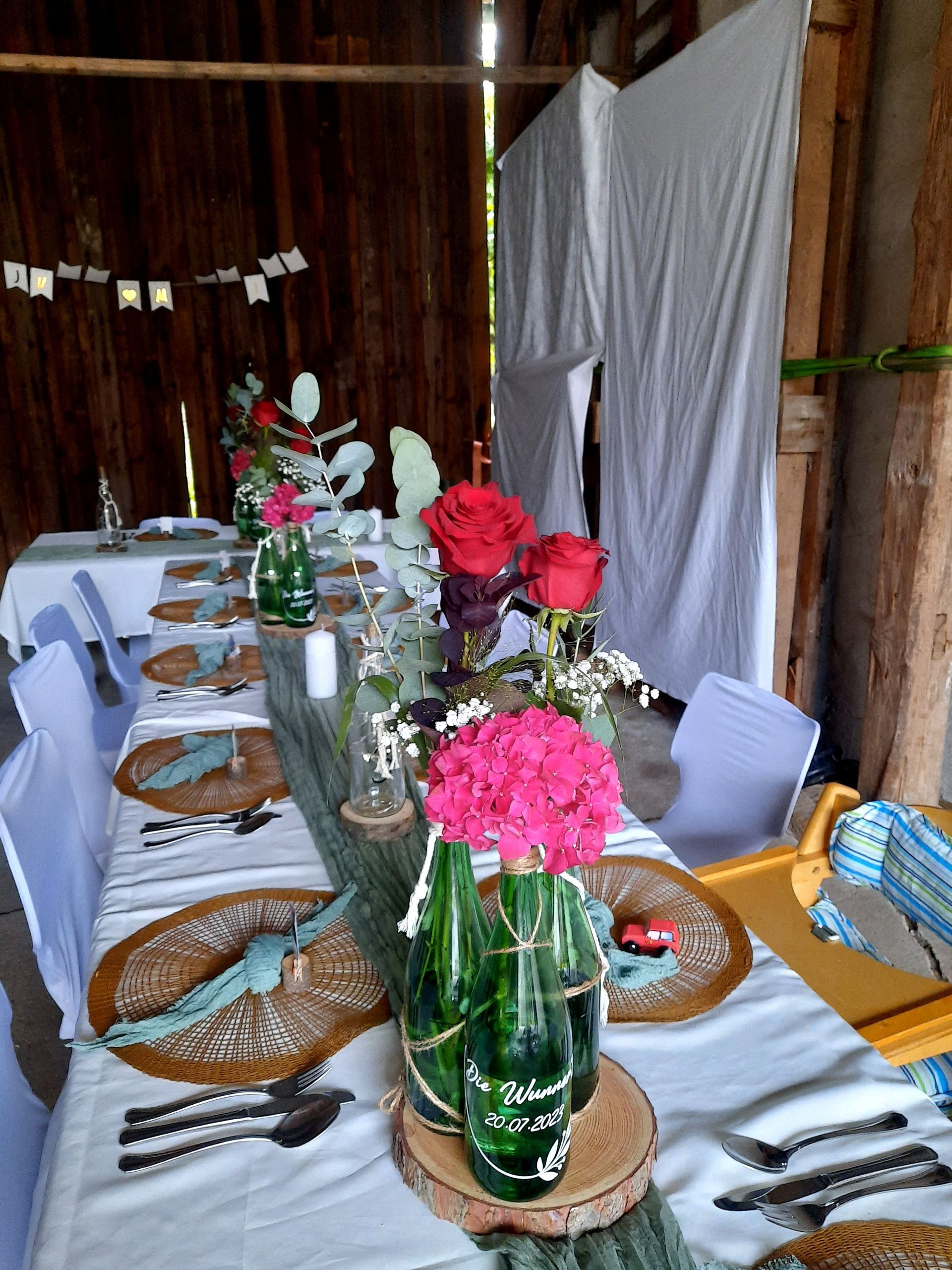Langer, für eine Party gedeckter Tisch mit Blumen, Gedecken und weißer Tischdecke.