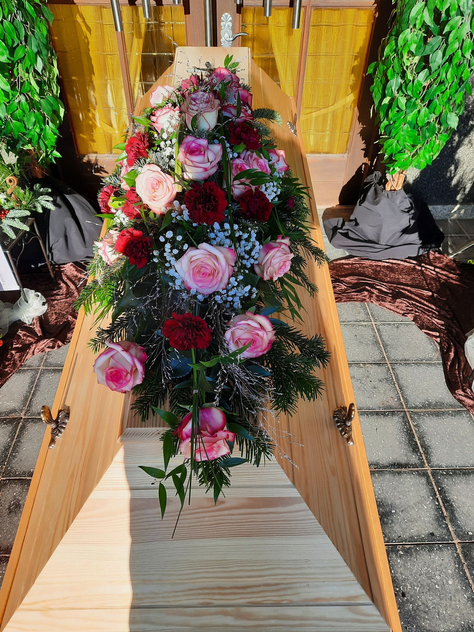 Trauersarg mit Blumenarrangement, im Freien.
