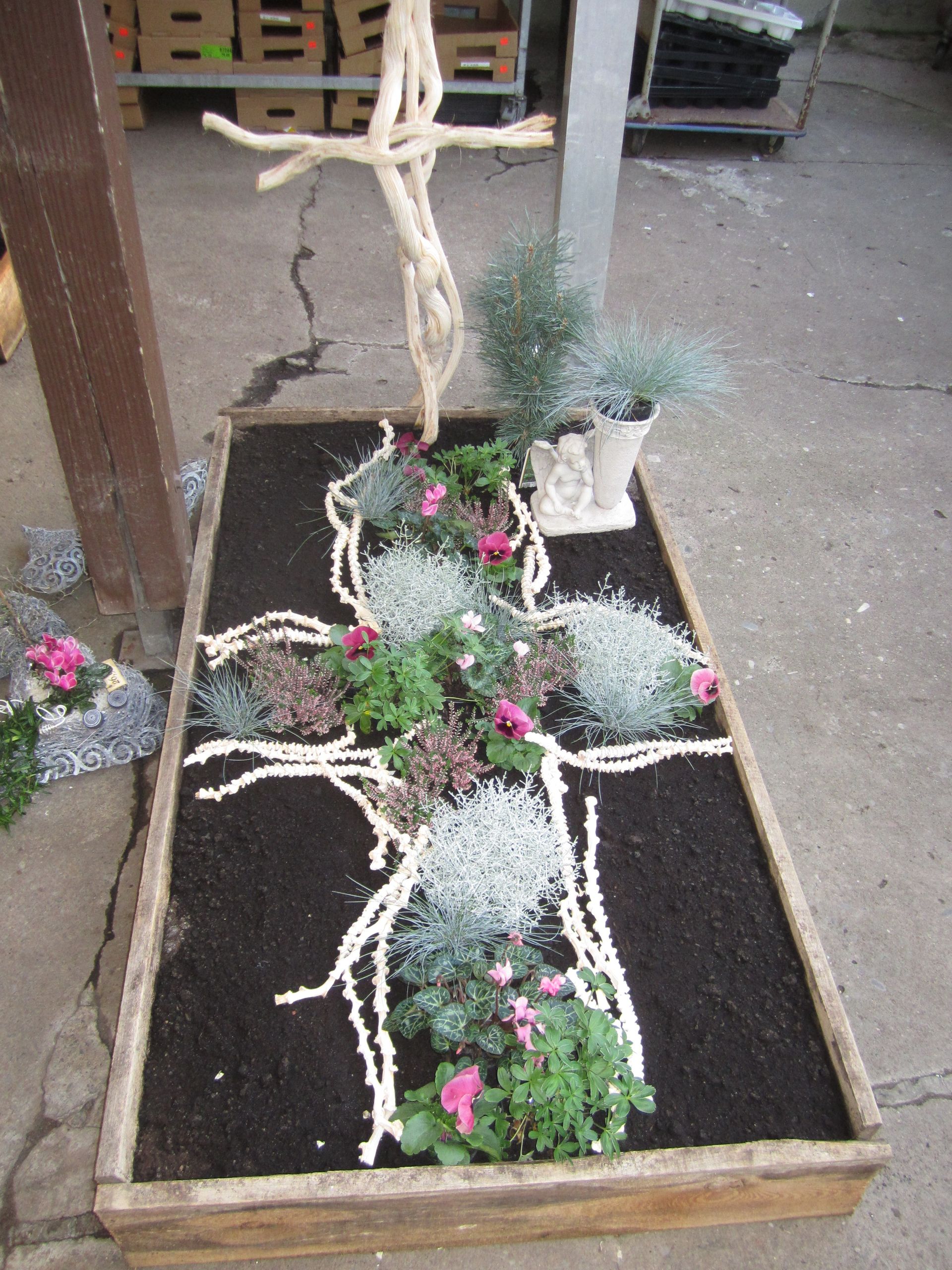 Grabschmuck mit einem Kreuz aus Seil, Blumen und Grün.