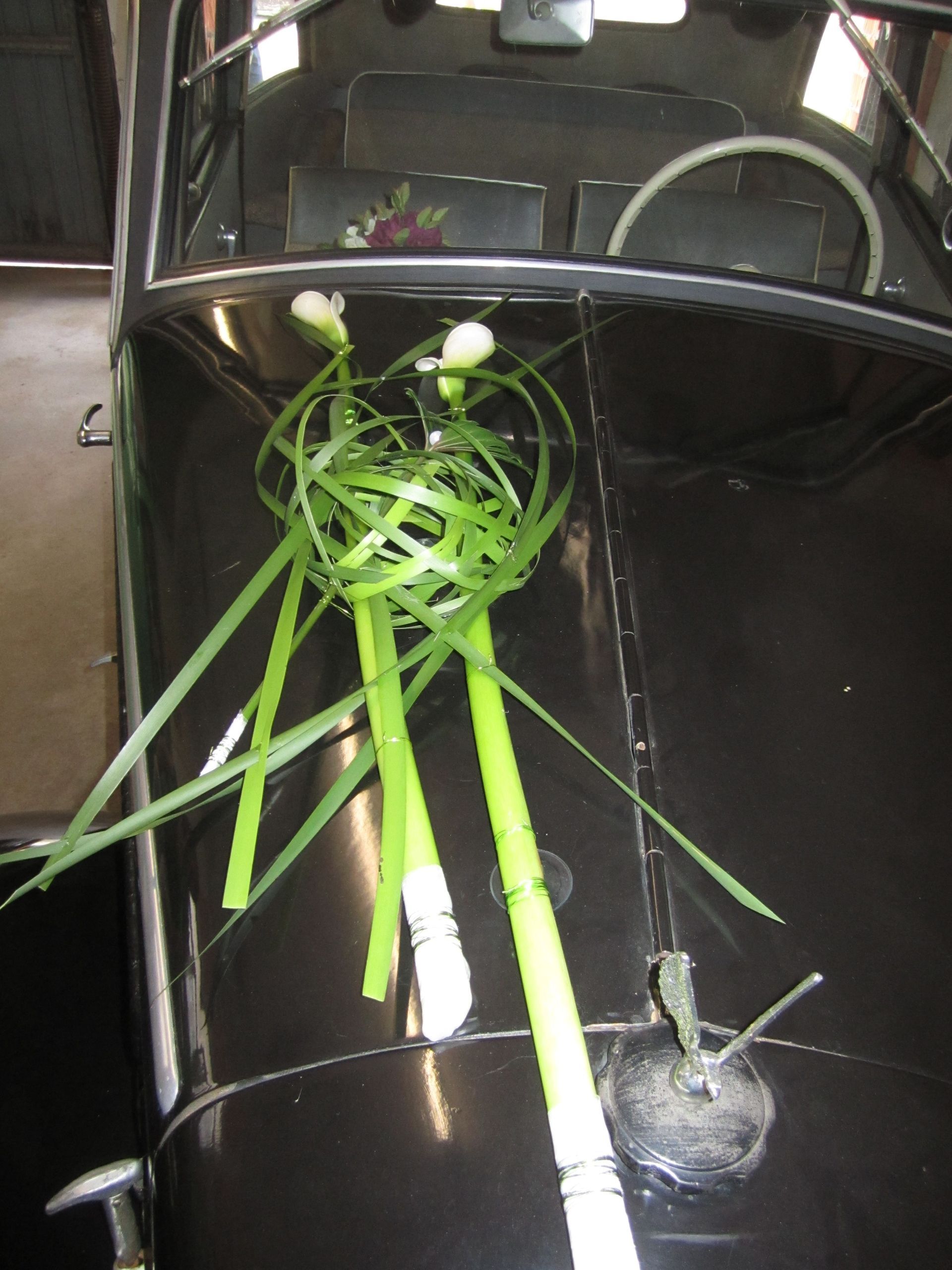 Schwarzer Oldtimer mit grünen Blumenakzenten dekoriert, drinnen.